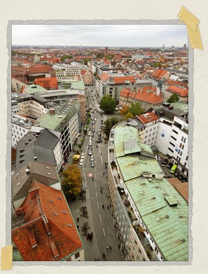 'A winding narrow street in Munich, complete with red brick and green copper roofs